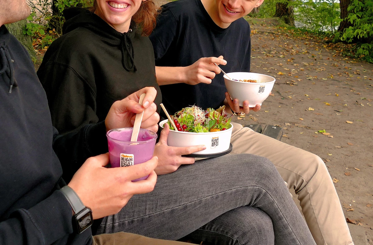 Tre människor som äter och dricker ut förpackningar från Relevo