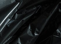 Närbild av skrynklig svart plastsäck som används för avfallshantering, med varierande struktur och veck. 
