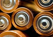 De positiva ändarna av flera aa-batterier placerade tätt intill varandra, visar metallklämmor och orangea höljen för förbrukning.