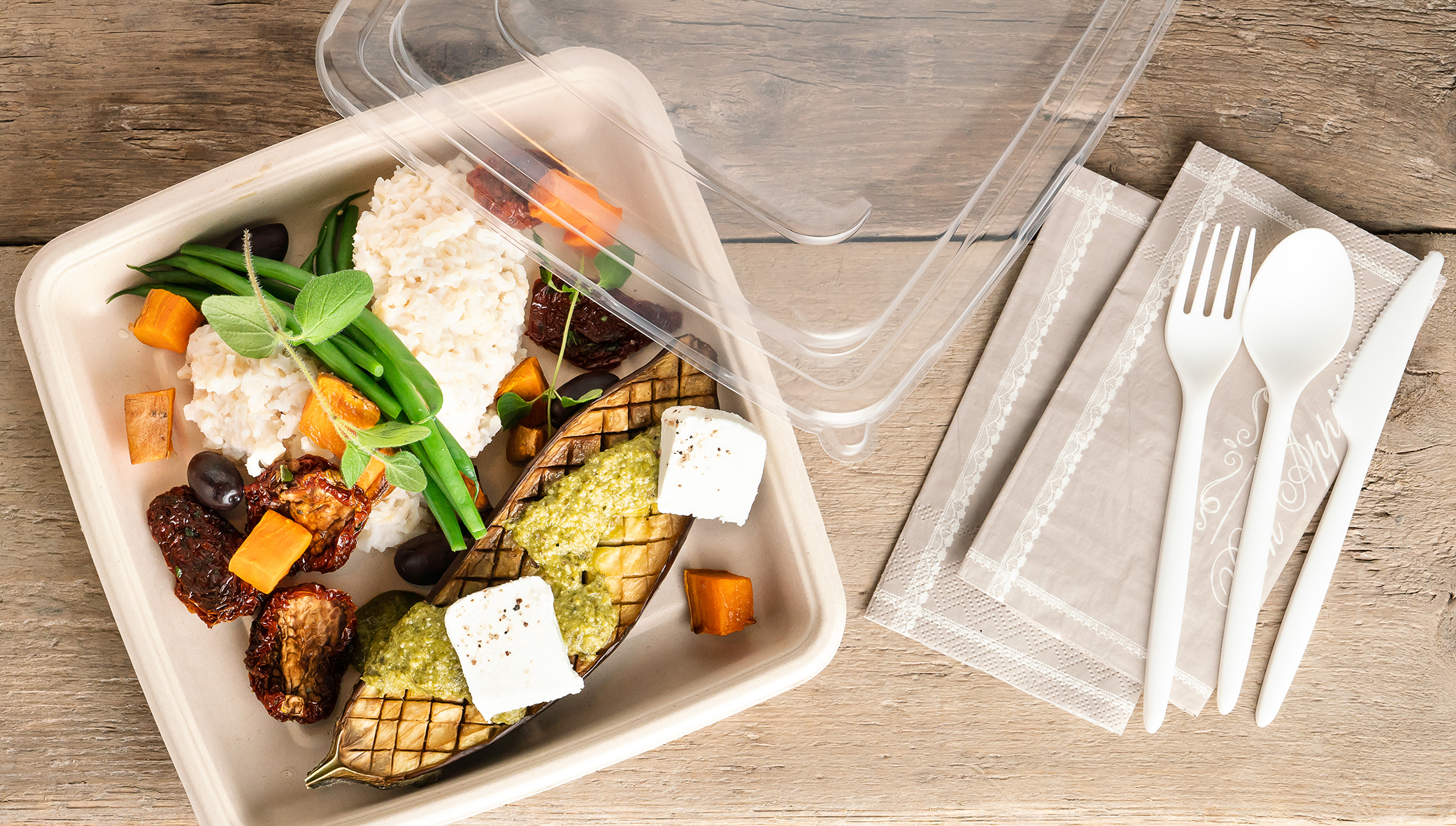 Matförpackning med mat i, engångsbestick och servetter bredvid
