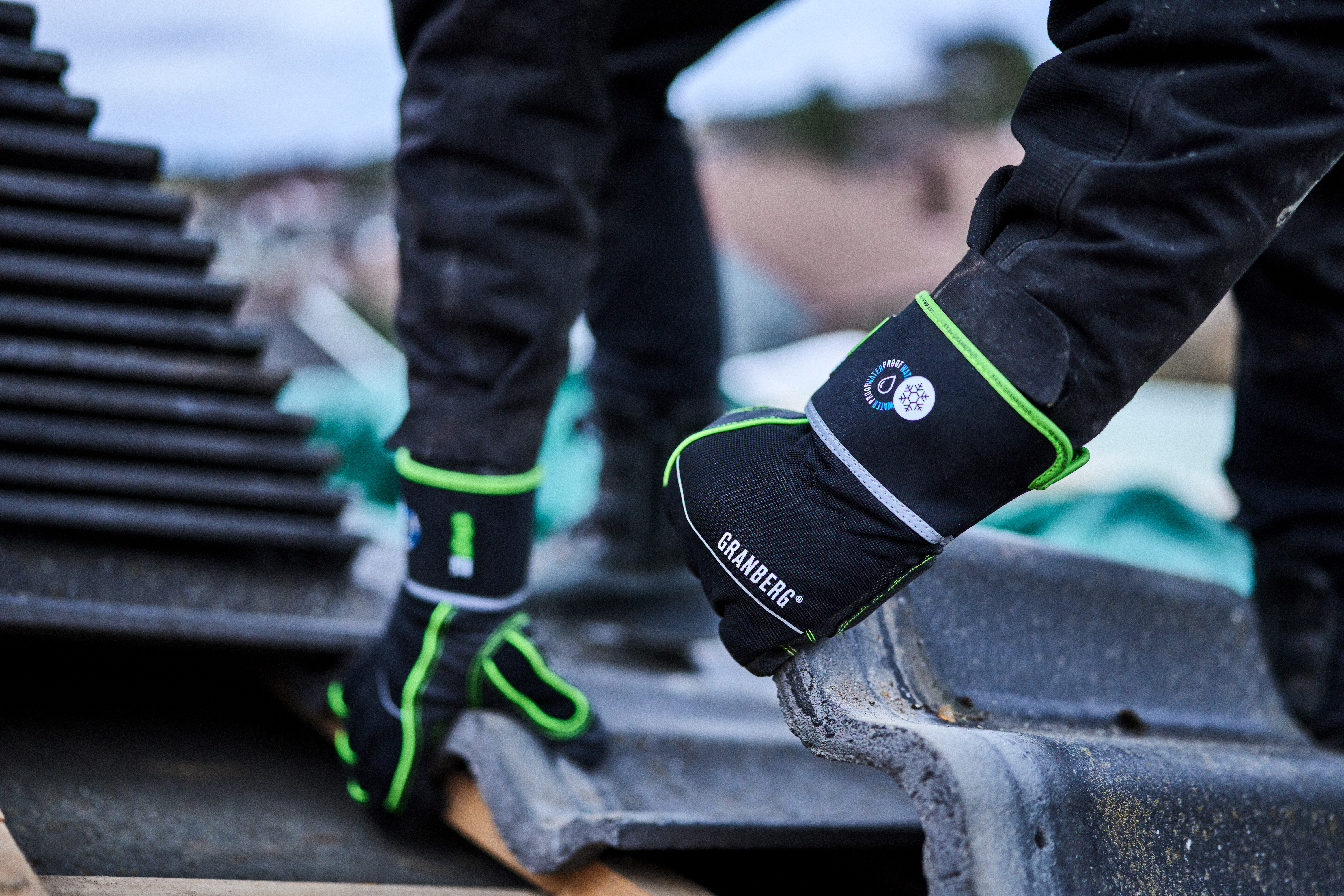 Person med vinterhandskar lägger takpannor på ett tak