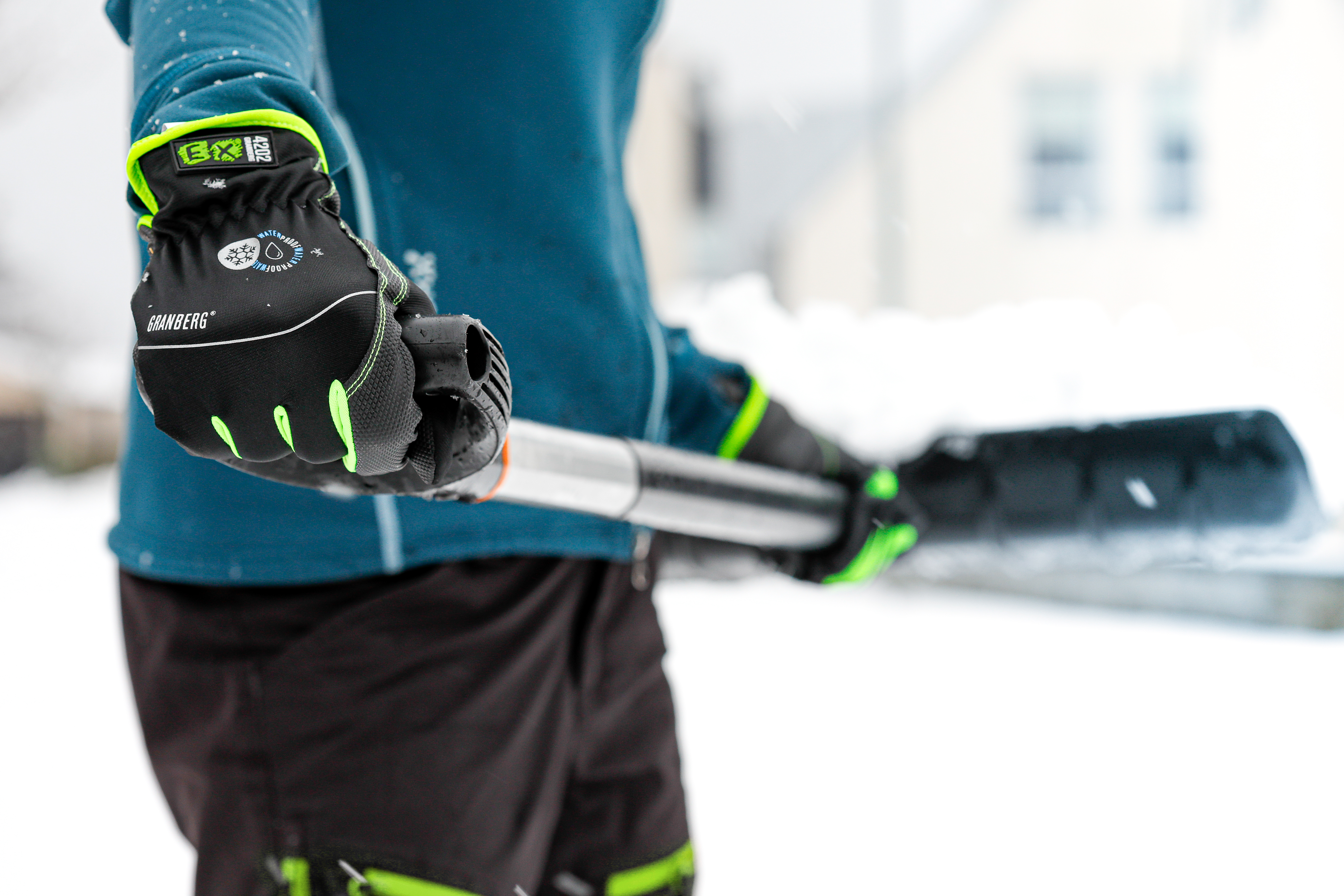 Någon håller en spade, har vinterhandskar  på sig, det är snö på marken